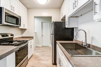 a kitchen with stainless steel appliances and white cabinets at Veranda La Mesa, La Mesa